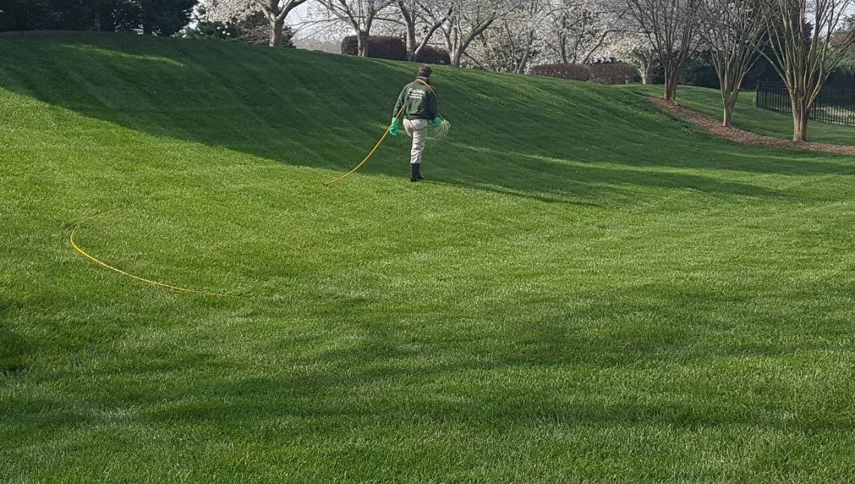 Worker applying liquid fertilizer to lawn in Charlotte, NC.